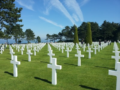 During the day, the green grass under the blue sky with a white cross
